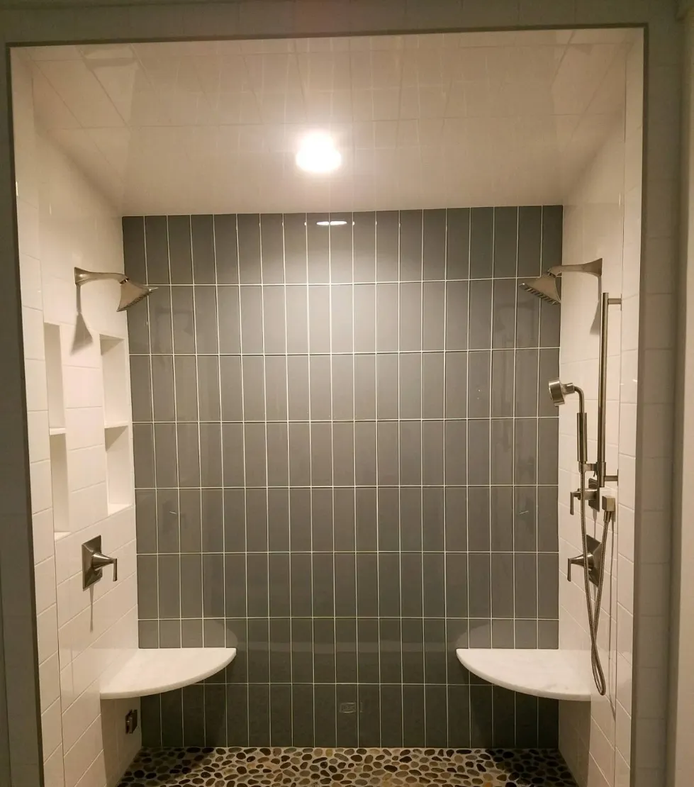Walk-in shower with vertical glass tile and pebble floor