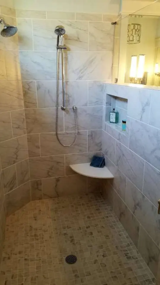 Marble walk-in shower with mosaic floor and corner bench